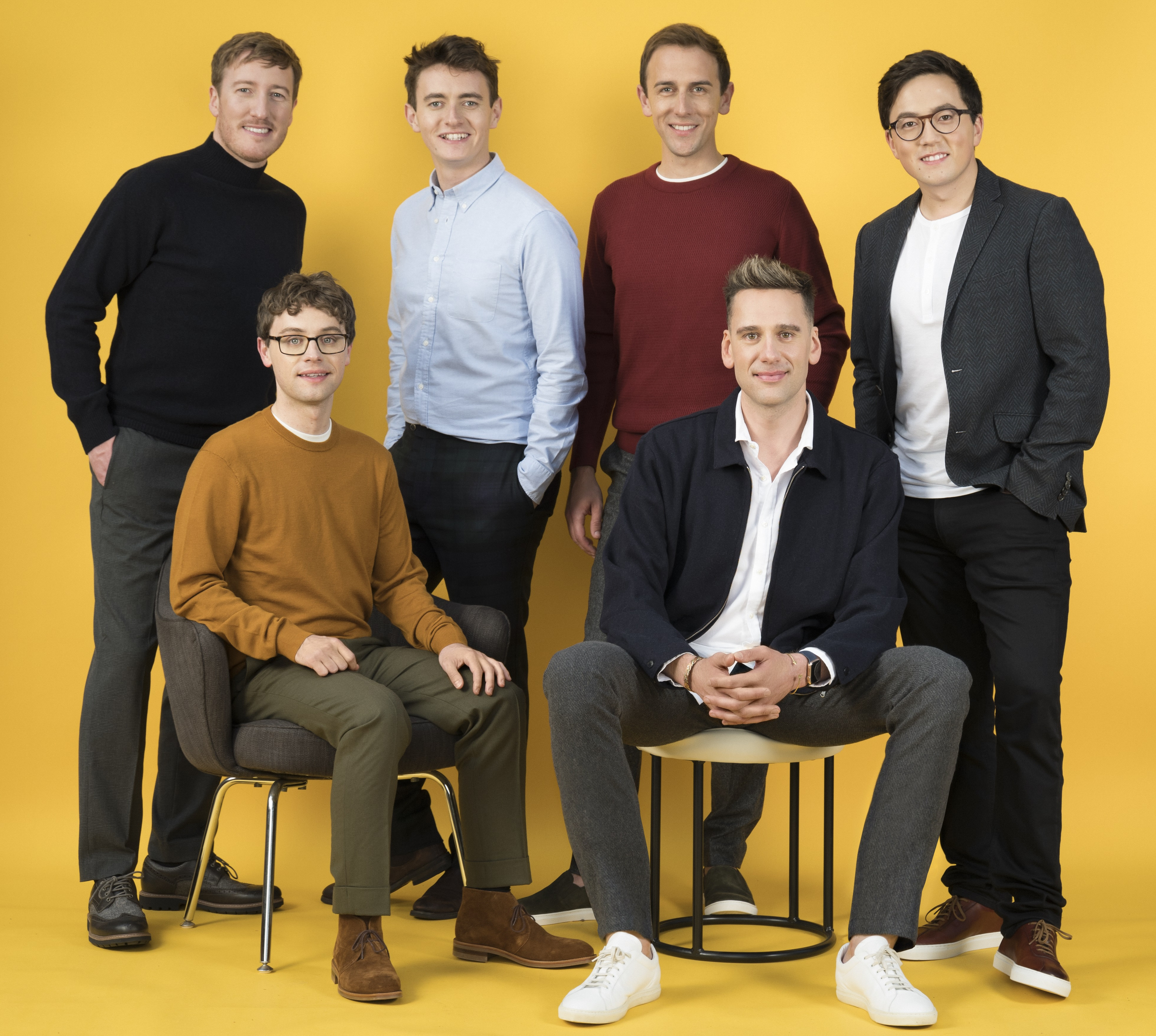 Sechs junge Männer in casual Business-Kleidung vor gelbem Hintergrund