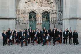 Ein gemischter Chor sitzt und steht vor einem grossen Kirchentor